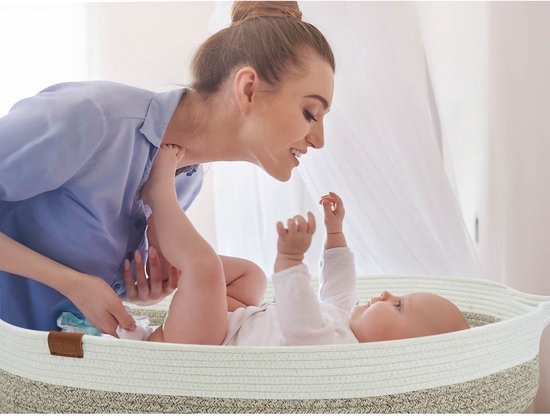 Moeder verschoont een baby in de beige verschoonmand