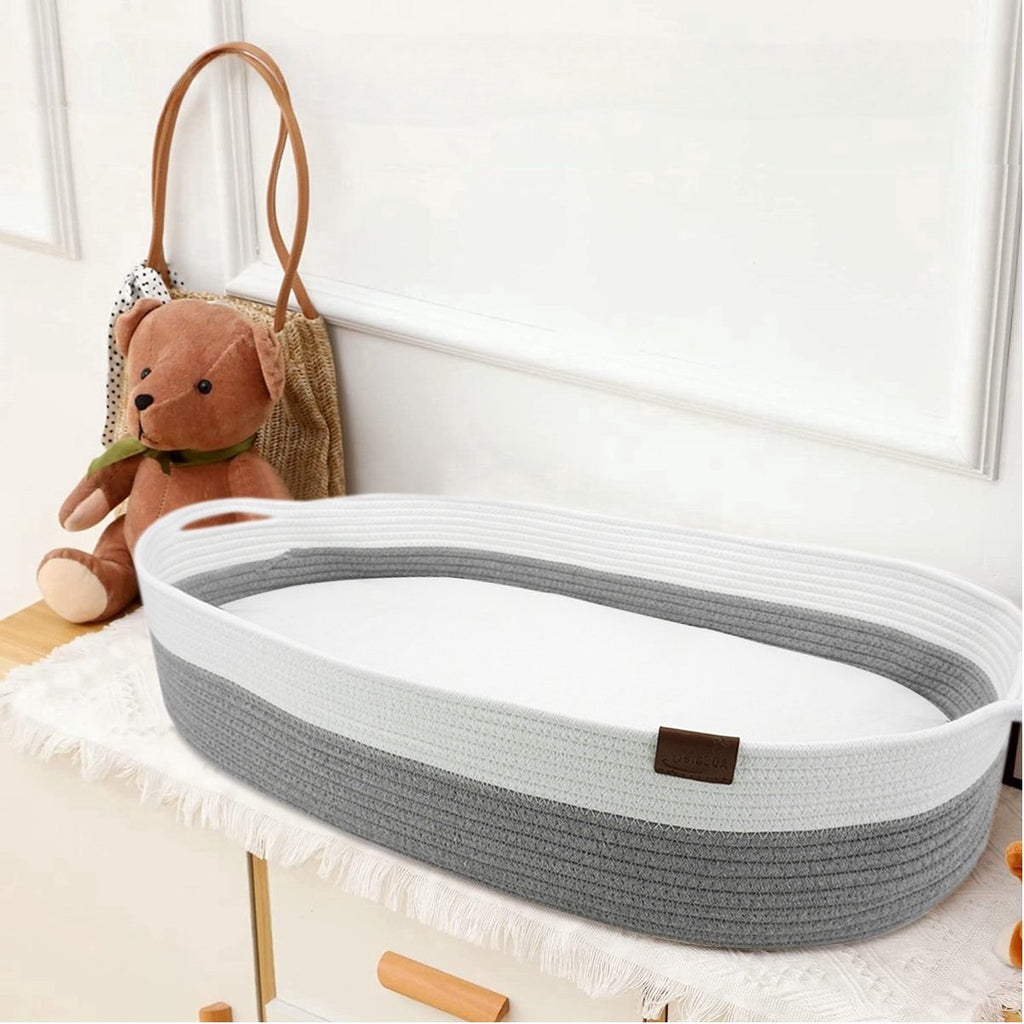 Grijze gevlochten verschoonmand met matrasje op een commode
